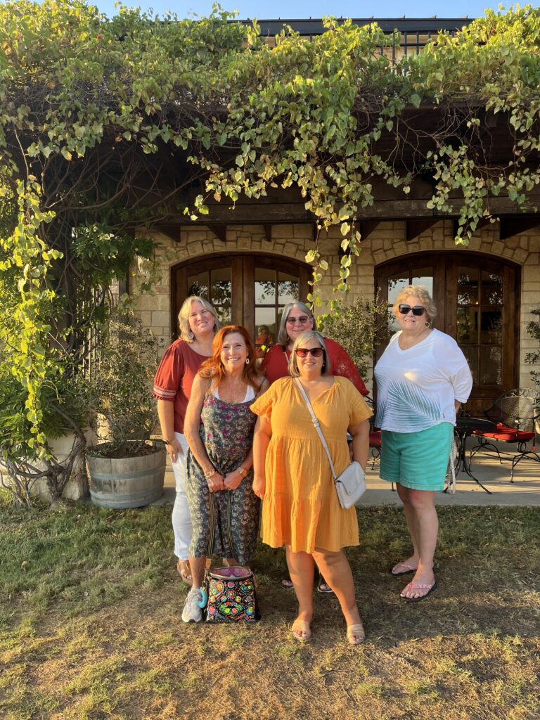 5 women in front of a house